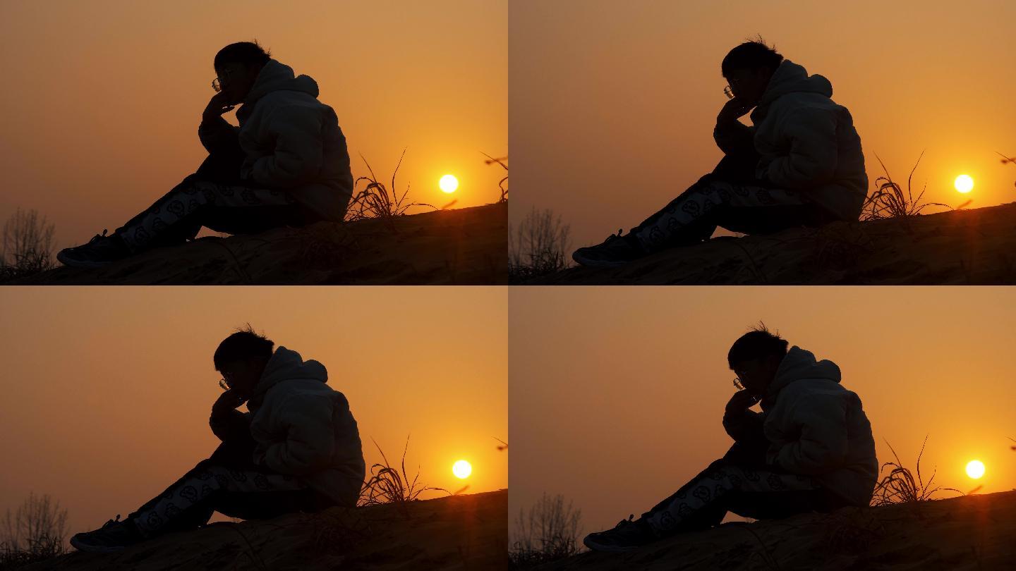 夕阳下坐在山峰上抑郁的男人