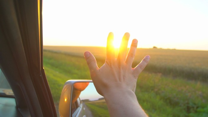日落时一个人的手从车窗伸出