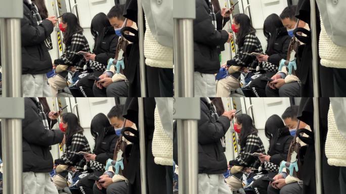 地铁列车上戴口罩的手机低头族