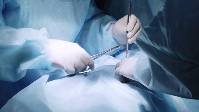 外科医生在切口缝合时使用工具的手