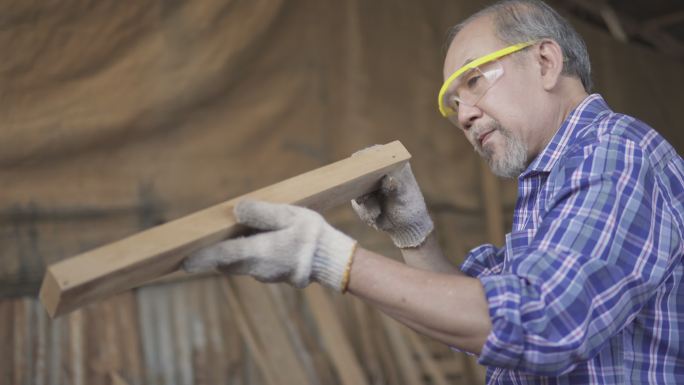 木匠佩戴护目镜，选择木材用于定制产品。