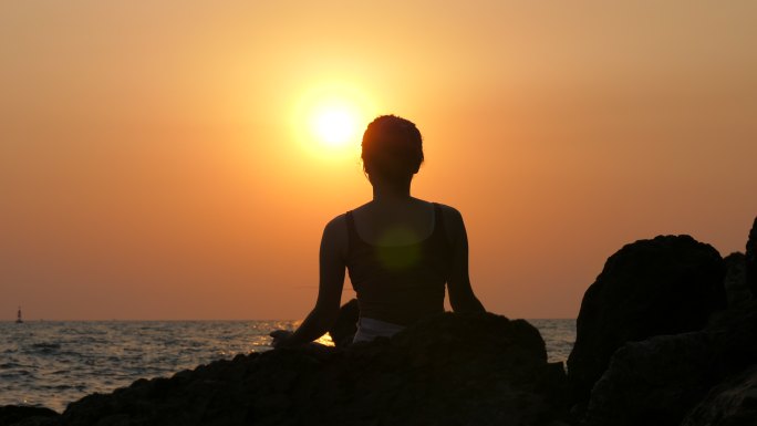 女性在看日落静坐打坐瑜伽