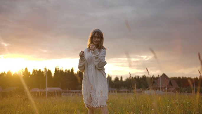 日落时在田野散步的快乐的女人