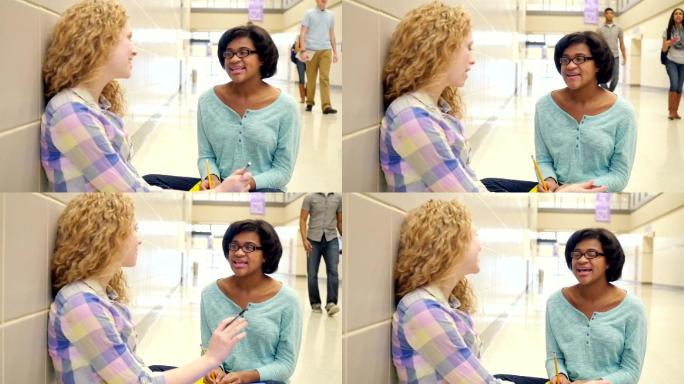 女孩坐在高中的走廊里与同学课后聊天