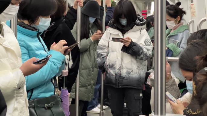 地铁列车车厢里的年轻人沉浸式玩手机