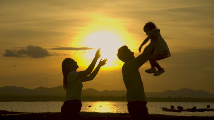 爸爸妈妈和女儿在日落时的海滩上玩耍。