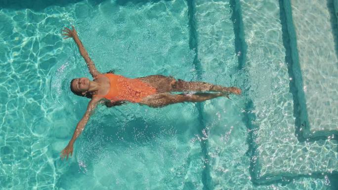 女孩在泳池里仰面游泳的慢镜头