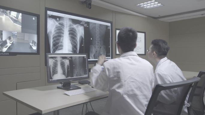 两个青年医生交流讨论患者胸部CT背影画面