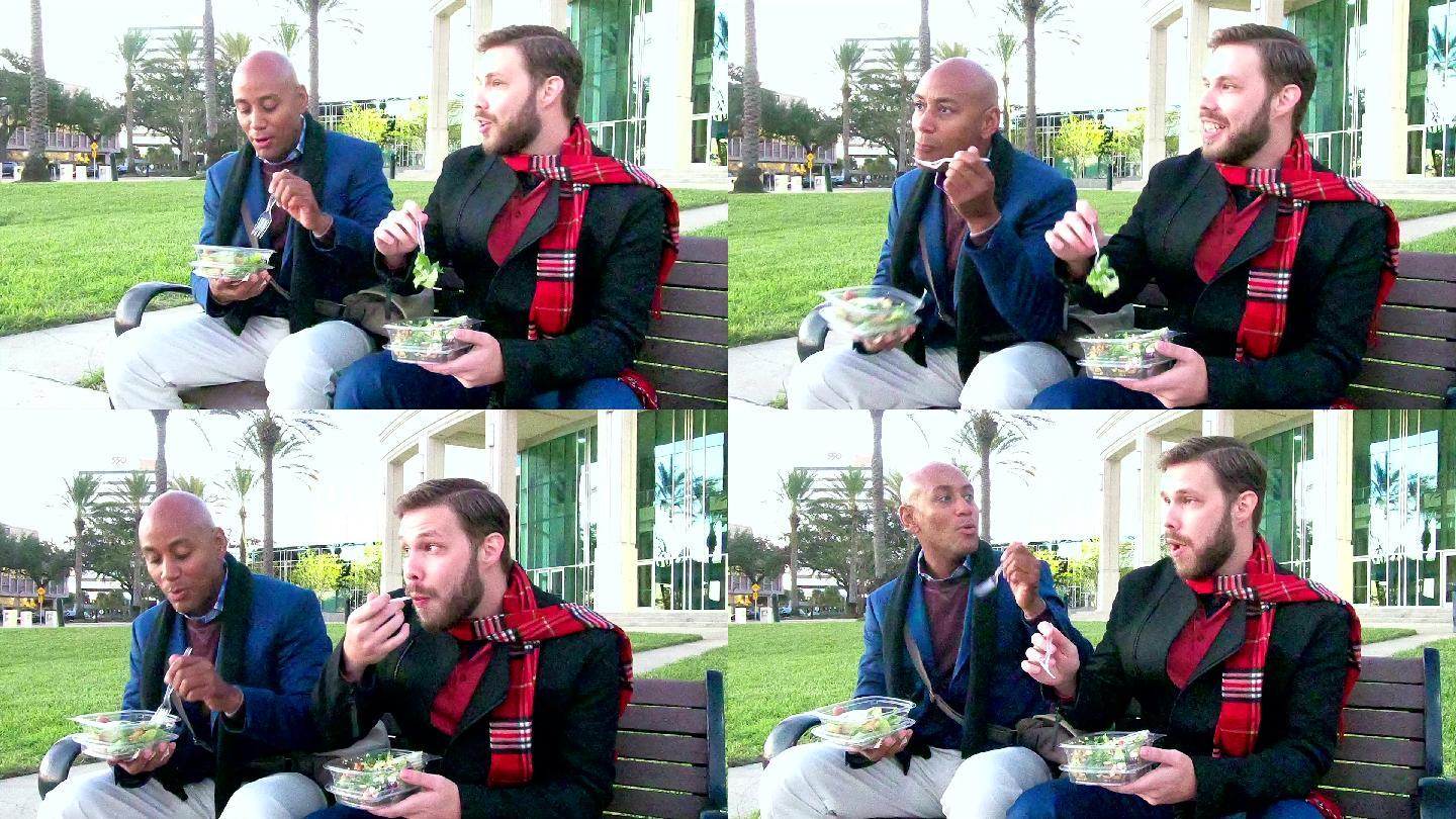 两个男人坐在长椅上吃午饭