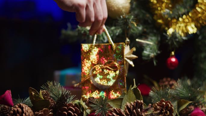 人类的双手正在圣诞树下放置一个礼品盒