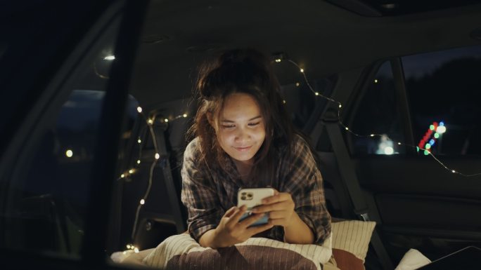 年轻女子在汽车露营中使用智能手机