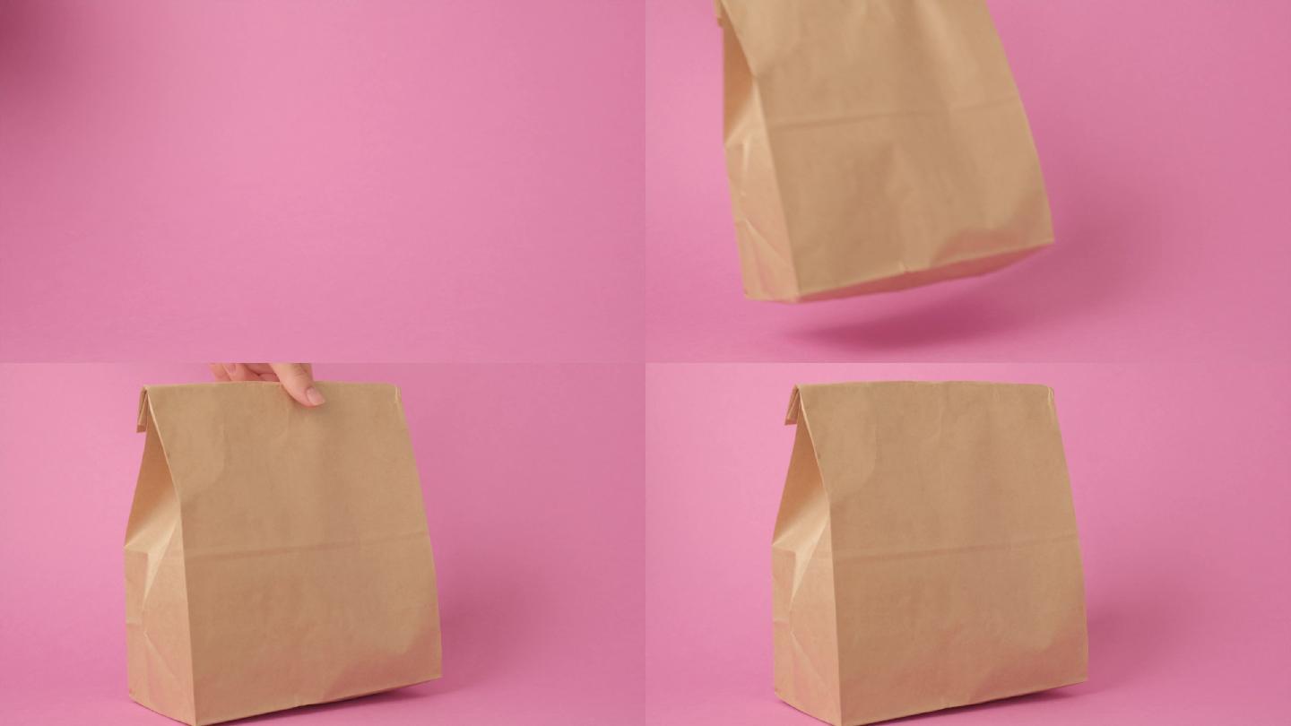 粉色背景的棕色空纸袋