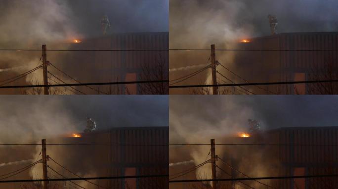 消防队员站在屋顶上缓慢地向火源移动