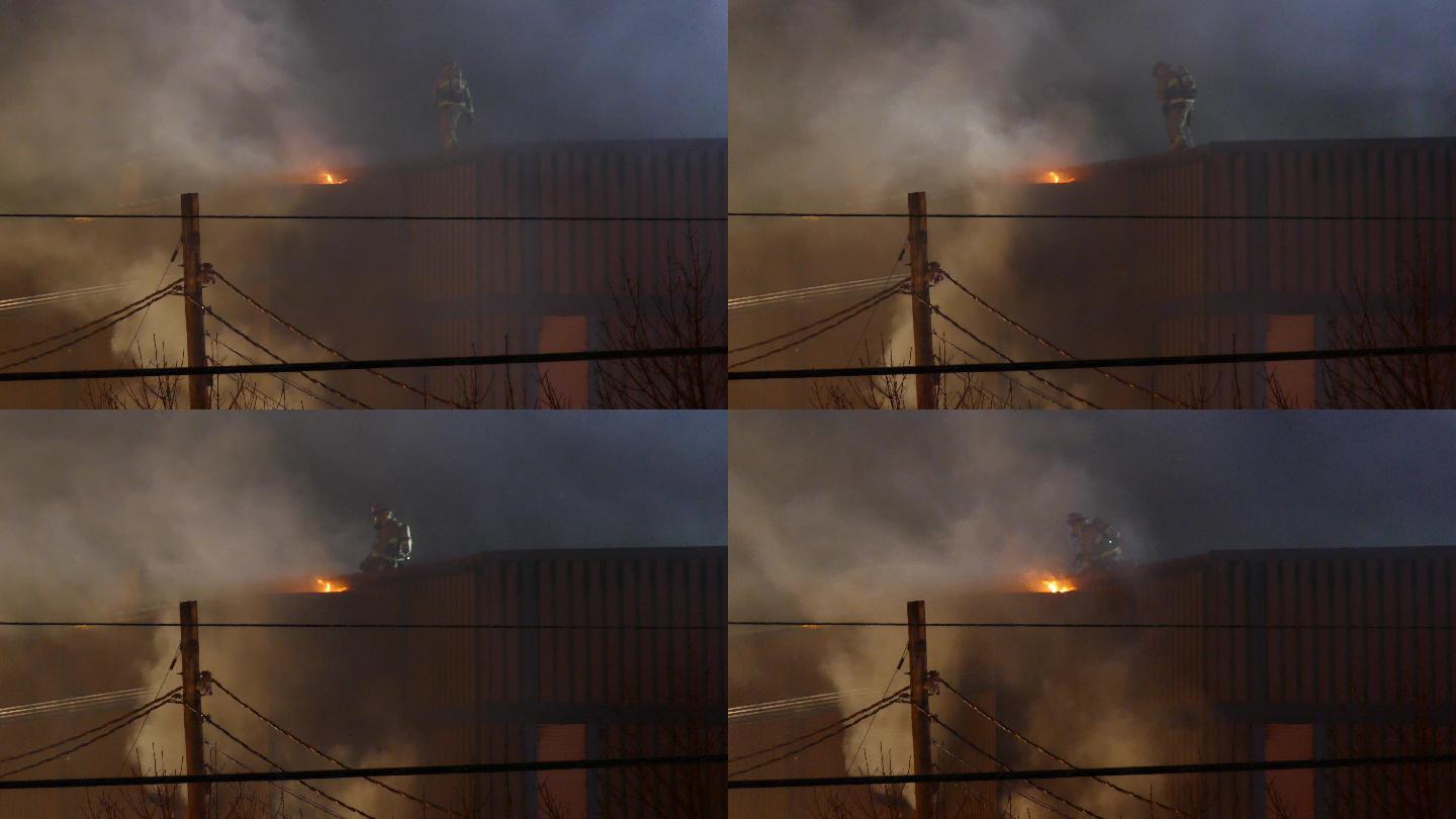 消防队员站在屋顶上缓慢地向火源移动