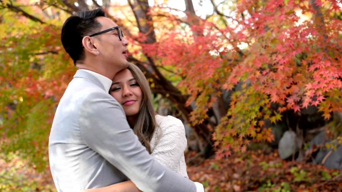 在红枫秋景中拥抱的幸福夫妻