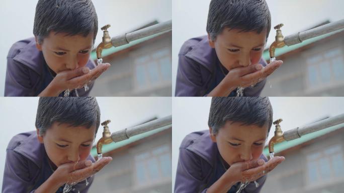 一个小男孩正在用自来水喝水