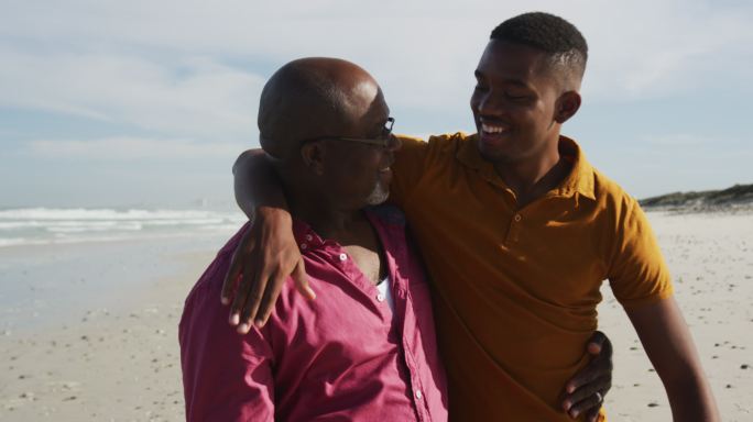 老人和儿子站在沙滩上拥抱和交谈