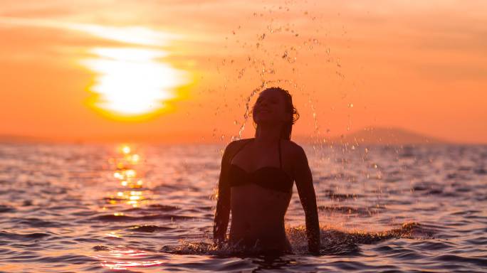 日落时留着长发的女人在海里耍水