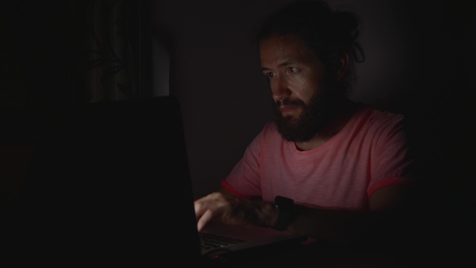 年轻人在黑暗中操作笔记本电脑