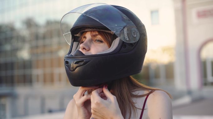 年轻漂亮的女摩托车手戴着黑色头盔。