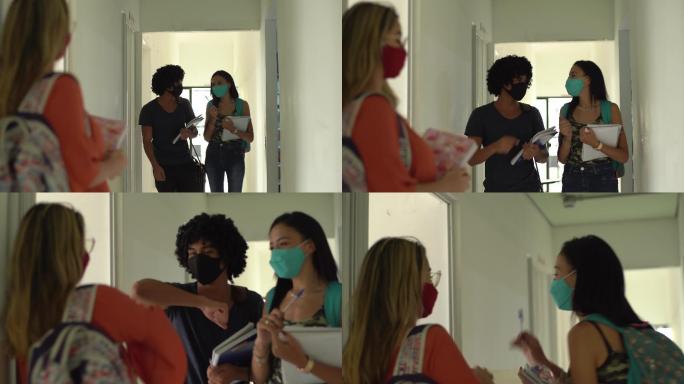 在大学走廊里，朋友们戴着口罩用肘部打招呼