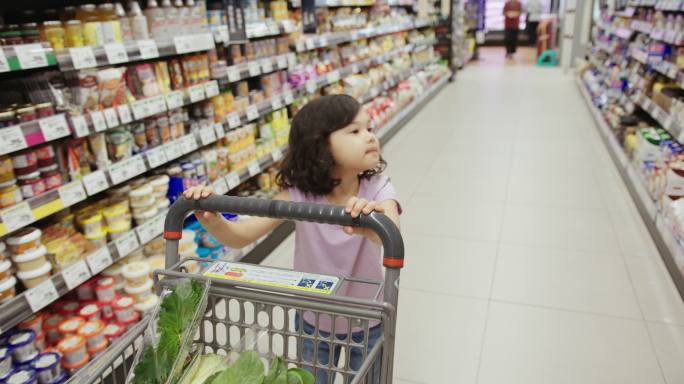 女孩在超市里快乐地推着购物车