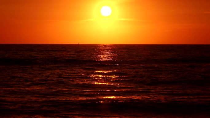 日落时，红色的太阳悬挂在水面上