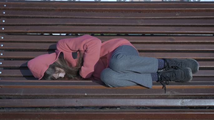 一个孩子睡在公园的长椅上。