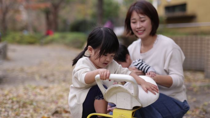 小女孩试图在公园里玩跷跷板