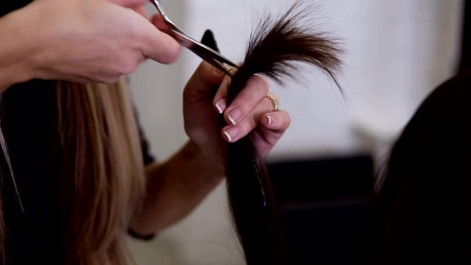 客户用新的金属剪刀剪棕色的发梢