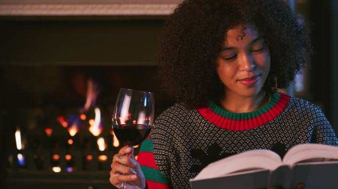 一名年轻女子在家休息时看书喝酒