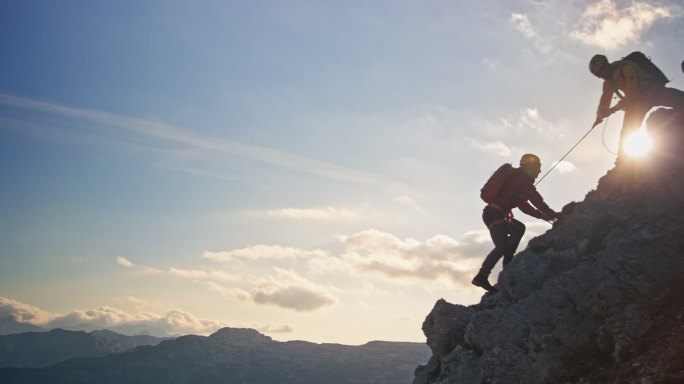 两位登山者在山顶下互相帮助