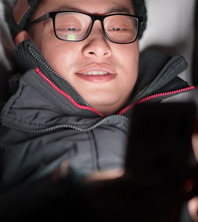年轻男躺在床上玩手机刷手机看视屏玩游戏