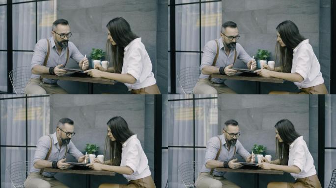 男子在咖啡馆向女友展示数码平板电脑
