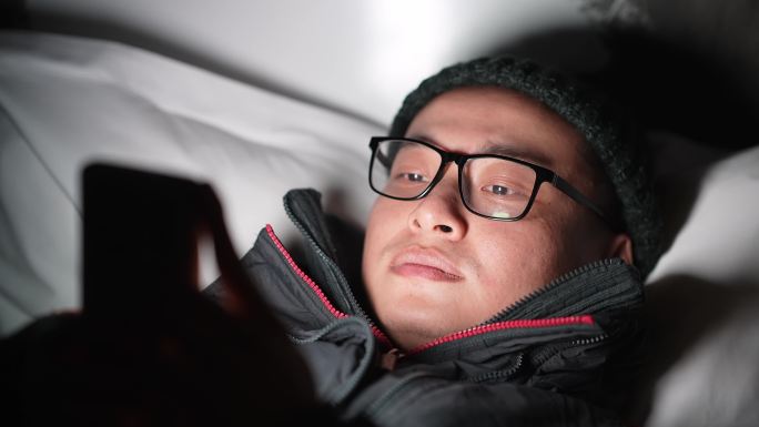 年轻男躺在床上玩手机刷手机看视屏玩游戏