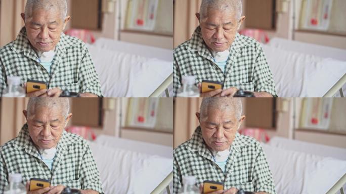 老年男性患者坐在病床上看着智能手机