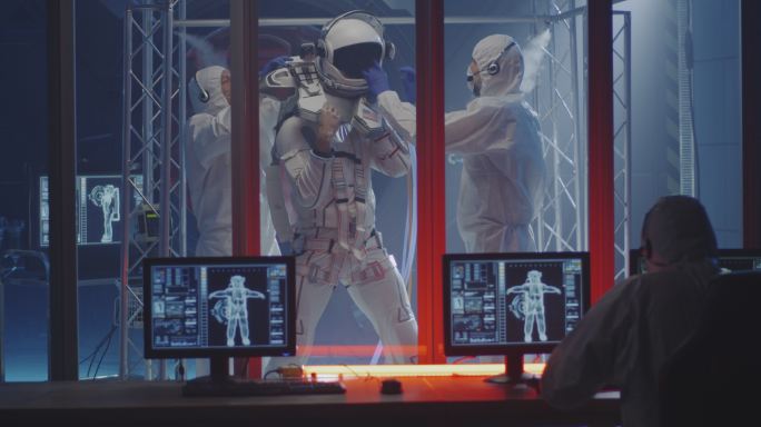 科学家帮助男性宇航员穿上宇航服的中镜头