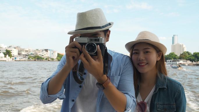夫妇乘船游览曼谷寺庙建筑河流城市景观