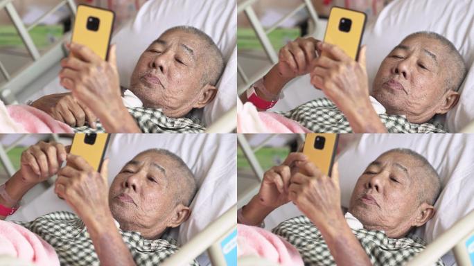老年男性患者躺在医院病床上，使用智能手机
