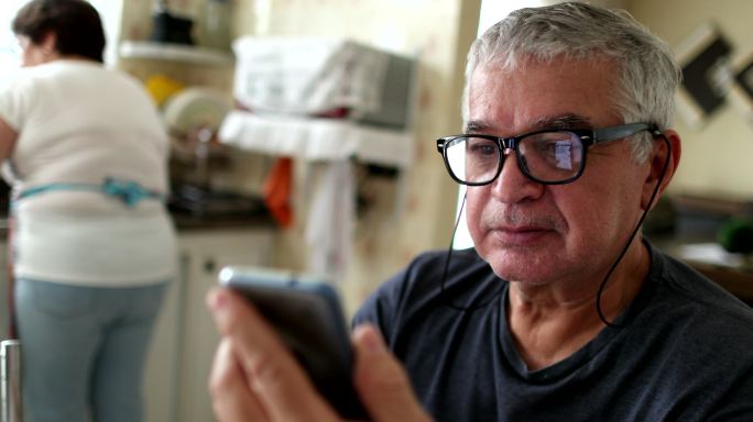 老人在家里通过智能手机阅读