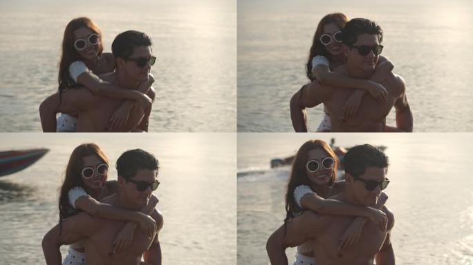 男人背着他的女朋友在海滩上玩耍