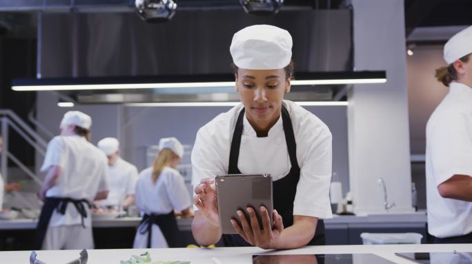 女厨师在餐厅厨房使用平板电脑