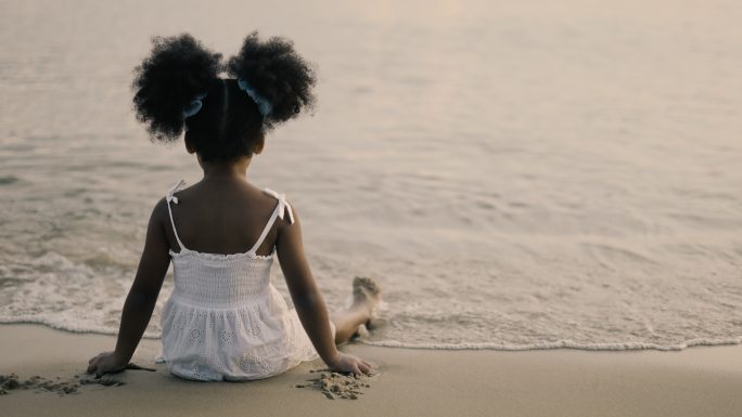 坐在海边的小女孩外国黑人小孩