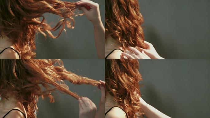 理发师轻轻地拉着女孩的红色卷发。