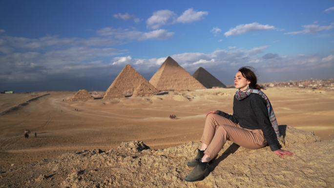 坐在吉萨金字塔附近沙漠中的女人