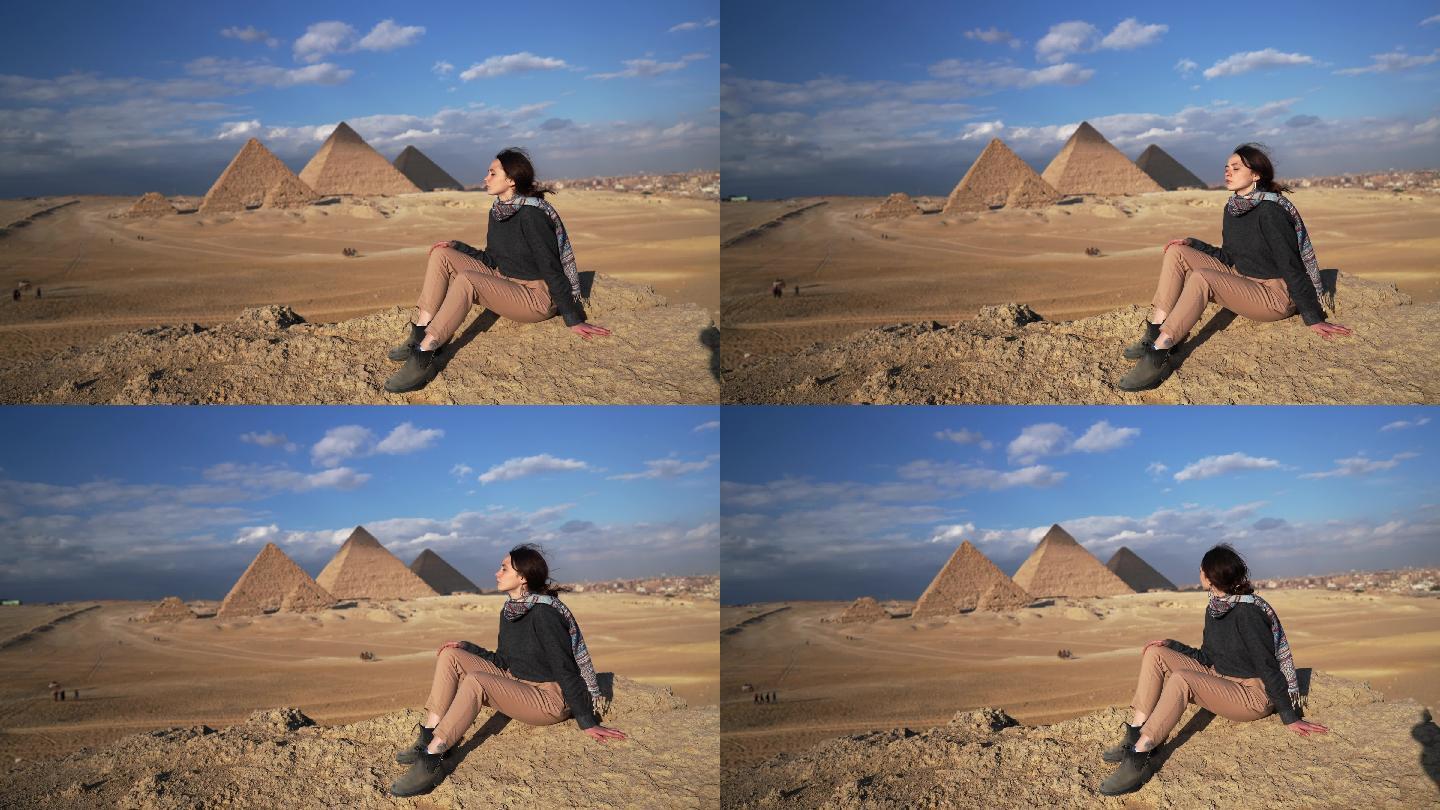 坐在吉萨金字塔附近沙漠中的女人