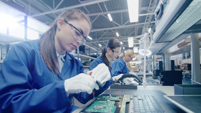 电子工厂女工人正在用螺丝刀组装笔记本电脑