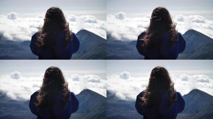 一名年轻女子在山上拍摄云朵。
