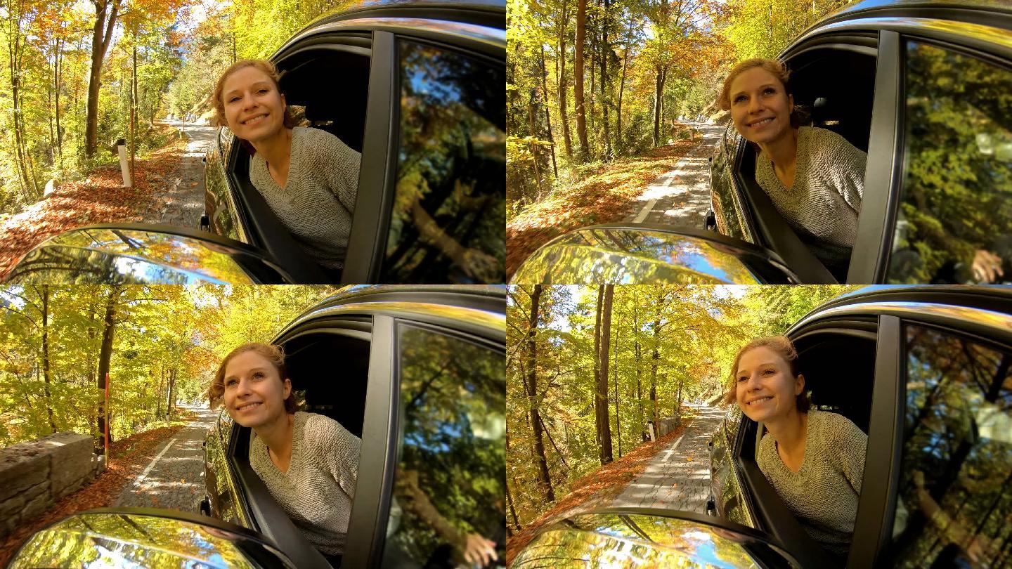 开车穿过秋天的森林时，一名女子探出车窗