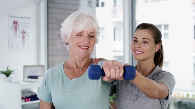 一名女性帮助老年患者进行锻炼